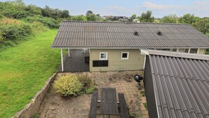 Una casa con tetto in metallo, un piccolo portico e un patio in legno.