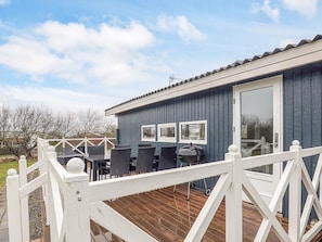 Ein kleines, eingeschossiges Gebäude mit einer Terrasse und Sitzgelegenheiten im Freien.