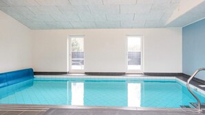 An indoor swimming pool with clear glass walls, a tiled floor, and a blue pool edge. - 5 Star Holiday Home in Glesborg (Glesborg)