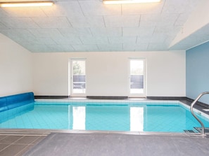 An indoor swimming pool with clear glass walls, a tiled floor, and a blue pool edge. - 5 Star Holiday Home in Glesborg (Glesborg)