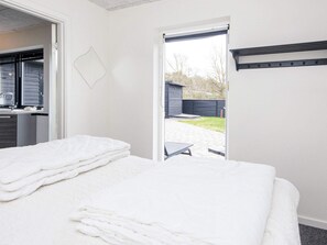 A hotel room with a bed, a desk with a chair, and a view of the outdoor area. - 5 Star Holiday Home in Glesborg (Glesborg)