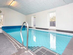 An indoor swimming pool with a metal ladder, tiled walls, and windows. - 5 Star Holiday Home in Glesborg (Glesborg)
