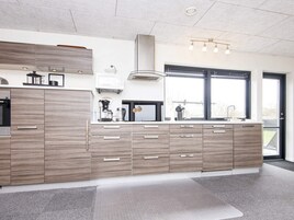 A modern kitchen with a large island, built-in appliances, and a window providing natural light.