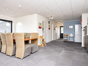 Un intérieur moderne comprenant un coin repas avec une table et des chaises, une cuisine équipée d’un réfrigérateur et un couloir agrémenté de portes et d’œuvres d’art.