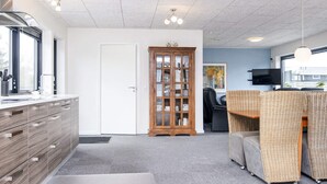 A modern interior with a kitchen area, a dining space, and a seating area with a television. - 5 Star Holiday Home in Glesborg (Glesborg)