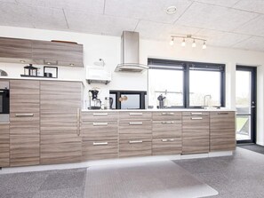 A modern kitchen with a large island, built-in appliances, and a large window. - 5 Star Holiday Home in Glesborg (Glesborg)