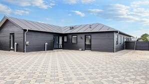 Un bâtiment à l’extérieur sombre, avec une entrée pavée et un ciel dégagé.