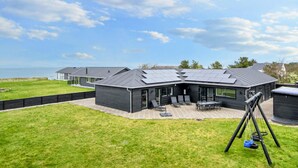 Une maison moderne dotée d’un patio, de panneaux solaires et d’une balançoire.
