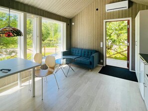 Un interior moderno con sofá, mesa de comedor, sillas y una lámpara colgante.