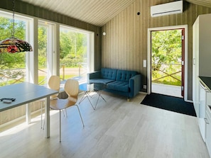 Un intérieur moderne avec un canapé, une table à manger, des chaises et un luminaire suspendu.