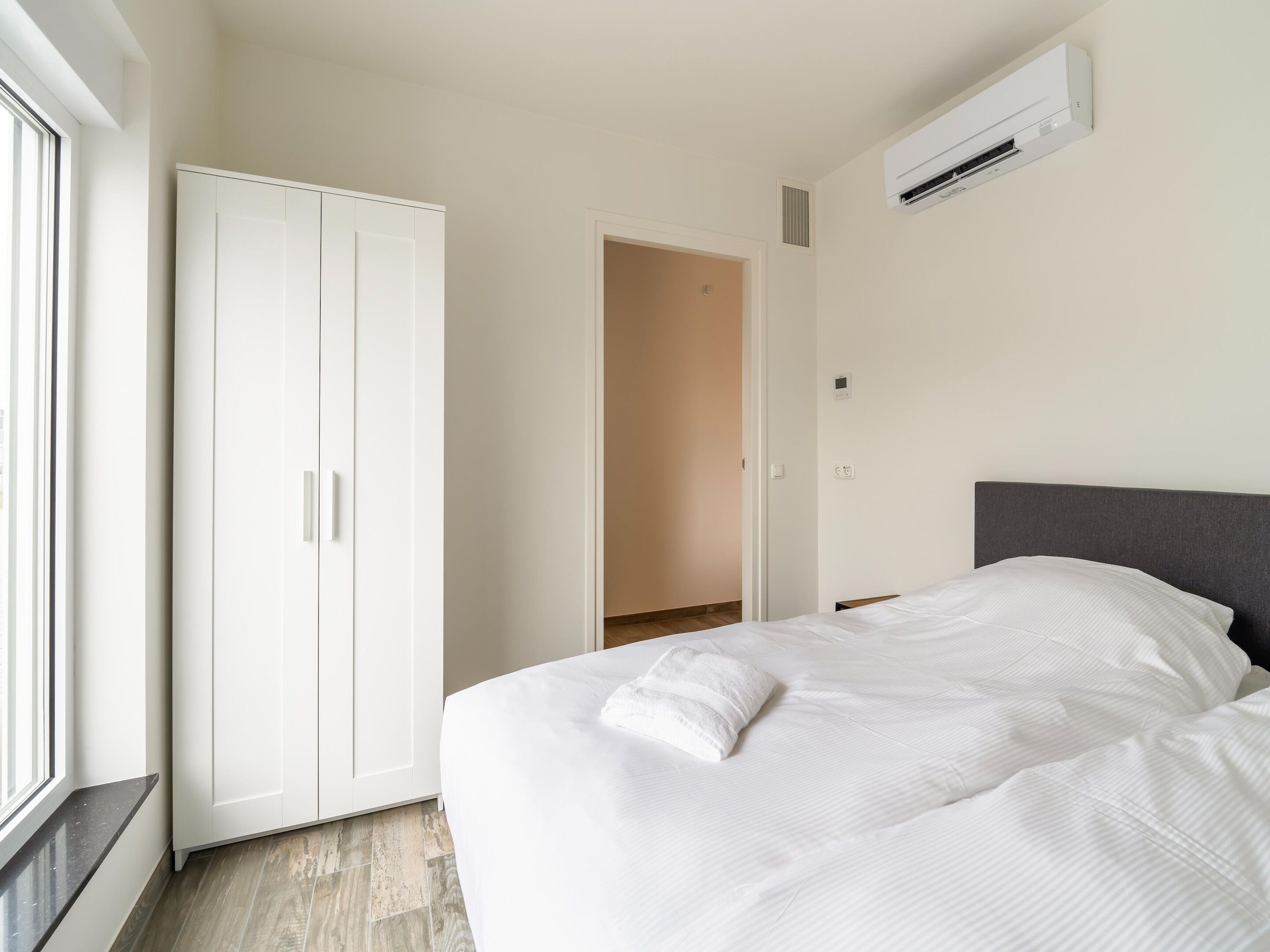 Ein Schlafzimmer mit einem Bett, einem Kleiderschrank und einem Fenster.