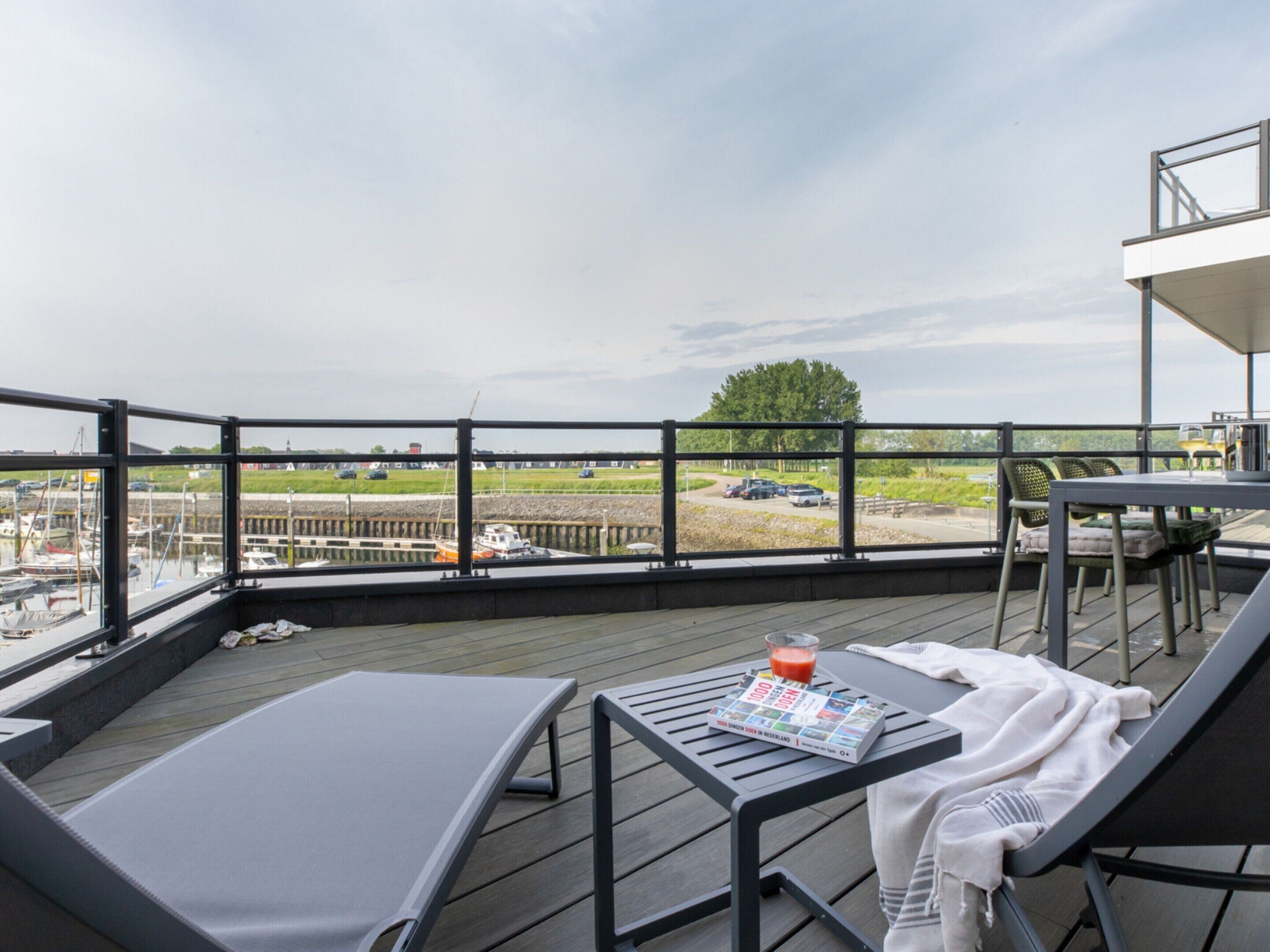 A balcony with a table, chairs, and a lounge chair.