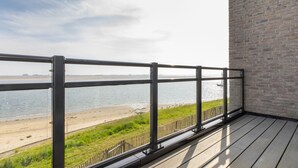 A balcony with a metal railing overlooking a beach and water.