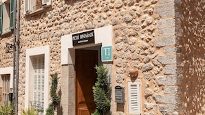 Un edificio de piedra con el letrero de un hotel boutique, una puerta de madera y plantas en macetas al frente.
