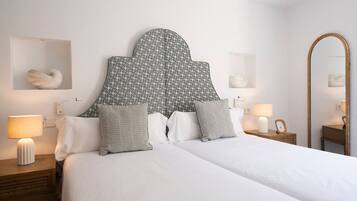 Una habitación de hotel con una cama grande, dos mesitas de noche, un espejo y una lámpara fijada a la pared.