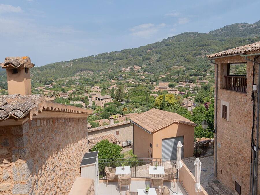 Terraza en la azotea con mobiliario exterior y vistas a un paisaje montañoso.