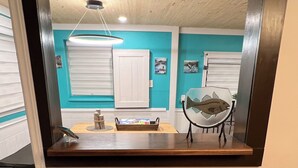 A kitchen with a wooden countertop, two stools, a hanging light fixture, and a large mirror above the counter. - Large 1 Bedroom Apartment in the Heart of Quidi Vidi (Ground Level) (St. John's)