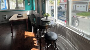 A kitchen with a wooden ceiling, a dining table with bar stools, and a window with a view of the street. - Large 1 Bedroom Apartment in the Heart of Quidi Vidi (Ground Level) (St. John's)
