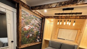 A bedroom with a large bed, a wooden headboard, a cityscape mural, and a wooden ceiling with exposed beams. - Large 1 Bedroom Apartment in the Heart of Quidi Vidi (Ground Level) (St. John's)