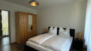 A bedroom with a large bed, wooden wardrobe, and a ceiling light. - Ferienhaus Eschborn, Frankfurt, Messe (Eschborn)