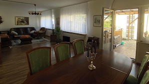 A dining room with a wooden table and chairs, a chandelier, and a view of the outdoors through a window. - Ferienhaus Eschborn, Frankfurt, Messe (Eschborn)
