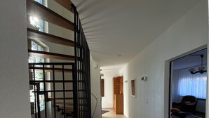 A modern interior with a staircase, a hallway leading to a room with a radiator, and a window with curtains. - Ferienhaus Eschborn, Frankfurt, Messe (Eschborn)