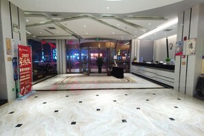 A hotel lobby with a marble floor, a reception desk, and a glass door entrance. - Huarong Jasmine Hotel (Huarong)