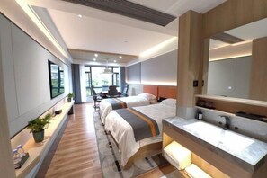 Een moderne hotelkamer met twee bedden, een grote spiegel, een wastafel met een wasbakje en een bureau met stoel.
