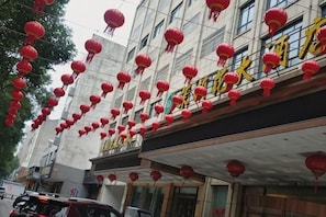 A building with multiple floors, red lanterns hanging from the exterior, and a sign with Chinese characters.