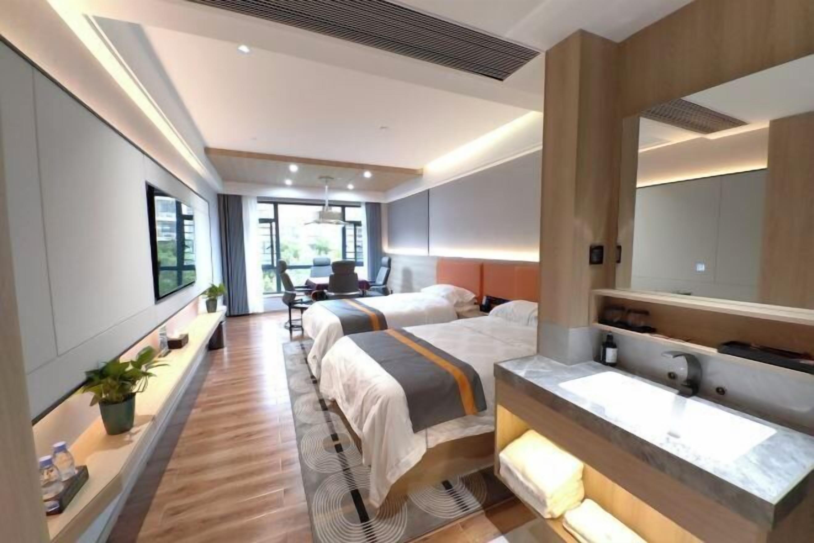 Habitación de hotel moderna con dos camas, un espejo grande, lavamanos integrado y vistas al exterior.