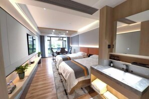 Een moderne hotelkamer met twee bedden, een grote spiegel, een ingebouwd wastafelmeubel en uitzicht op het omliggende landschap.