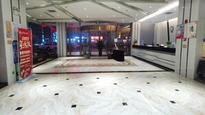 A hotel lobby with a marble floor, a reception desk, and glass doors leading to another area. - Huarong Jasmine Hotel (Huarong)