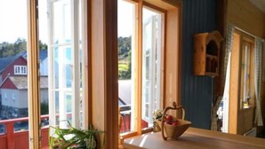 A room with large windows, a wooden table, and a chair. - Charming sea house with private sauna & jetty with direct access to the fjord (Vestland)