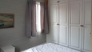 A bedroom with a bed, a wardrobe, a nightstand, and a painting on the wall. - Charming sea house with private sauna & jetty with direct access to the fjord (Vestland)