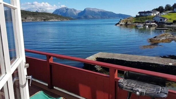 A view from a window overlooking a calm lake with mountains in the background and a small harbor with boats and houses. - Charming sea house with private sauna & jetty with direct access to the fjord (Vestland)