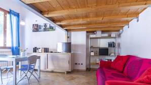 A compact living space with a dining area, a kitchenette, and a red sofa.