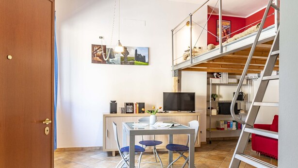 A compact living space with a bunk bed, a desk with a computer, and a TV.