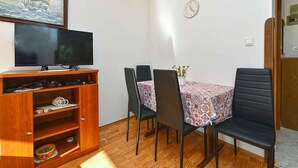 A dining area with a wooden cabinet, a television, and a table with chairs. - Holiday apartment with air conditioning (Rovinj)