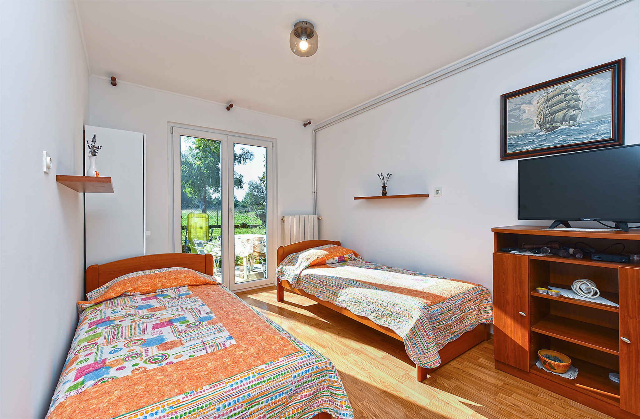 A bedroom with two single beds, a TV, a wooden cabinet, and a painting on the wall.