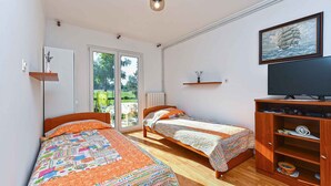 A bedroom with two single beds, a TV, a wooden cabinet, and a painting on the wall. - Holiday apartment with air conditioning (Rovinj)