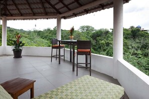 Un área de estar al aire libre cubierta con una mesa y dos sillas, rodeada de abundante follaje.