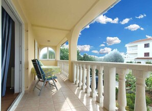 Ein Balkon mit Blick auf ein weißes Gebäude und Grünflächen.
