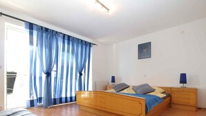 Un dormitorio con una cama de madera, una mesita de noche, una lámpara y una ventana con cortinas azules.