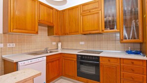 A kitchen with wooden cabinets, a dishwasher, an oven, and a sink. - Holiday apartment with terrace (Vinkuran)
