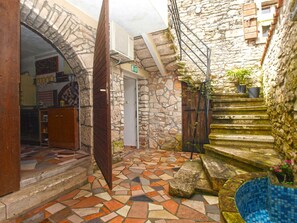 Step into a charming courtyard with a stone wall, wooden door, and mosaic-tiled floor.