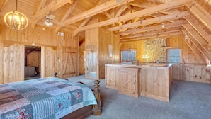 A wooden cabin with a loft bedroom, a stone wall, and a kitchen area. - Avoid The Traffic Jams 7acres 360 Views 7b 4 5b (Sevierville)