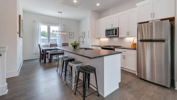 A modern kitchen with white cabinetry, stainless steel appliances, and a central island with bar stools. - Modern 3 3 in East Nash 10min to Broadway (Nashville)