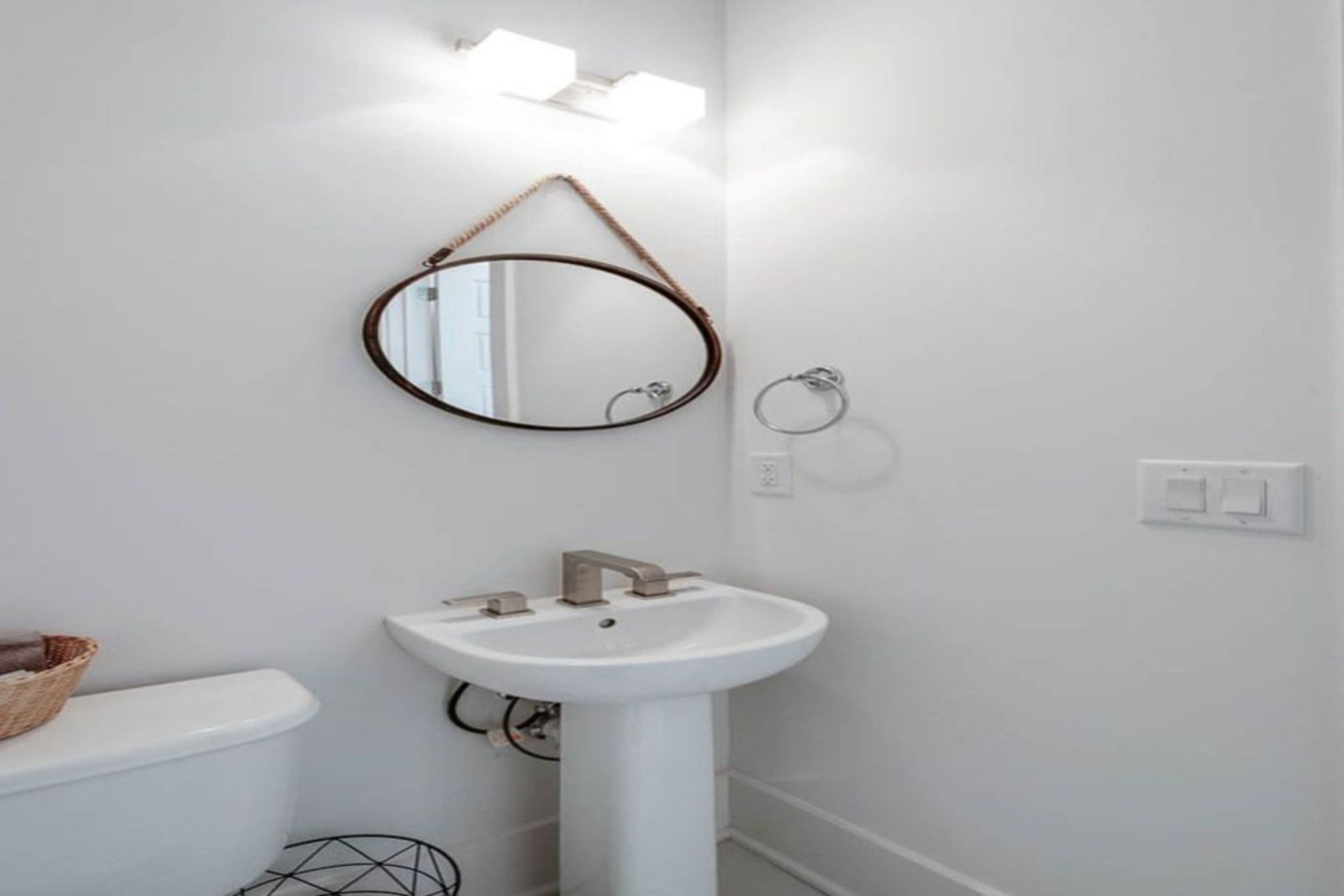 A bathroom with a white sink, a round mirror, and a toilet.