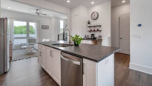 A modern kitchen with white cabinets, a granite countertop, and a built-in dishwasher. - Modern 3 3 in East Nash 10min to Broadway (Nashville)