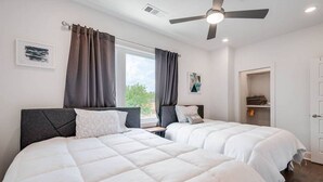 A bedroom with two beds, a ceiling fan, a window with curtains, and a door leading to a closet. - Modern 3 3 in East Nash 10min to Broadway (Nashville)